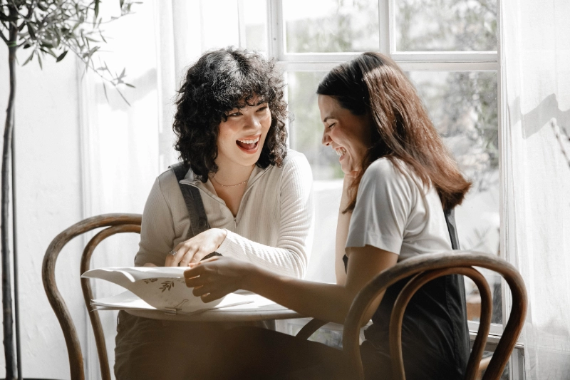 Twee vrouwen aan de tafel lachen